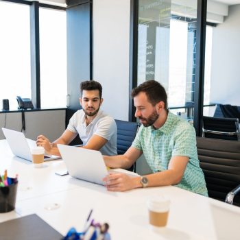 Businessmen using laptop while sitting at desk in office